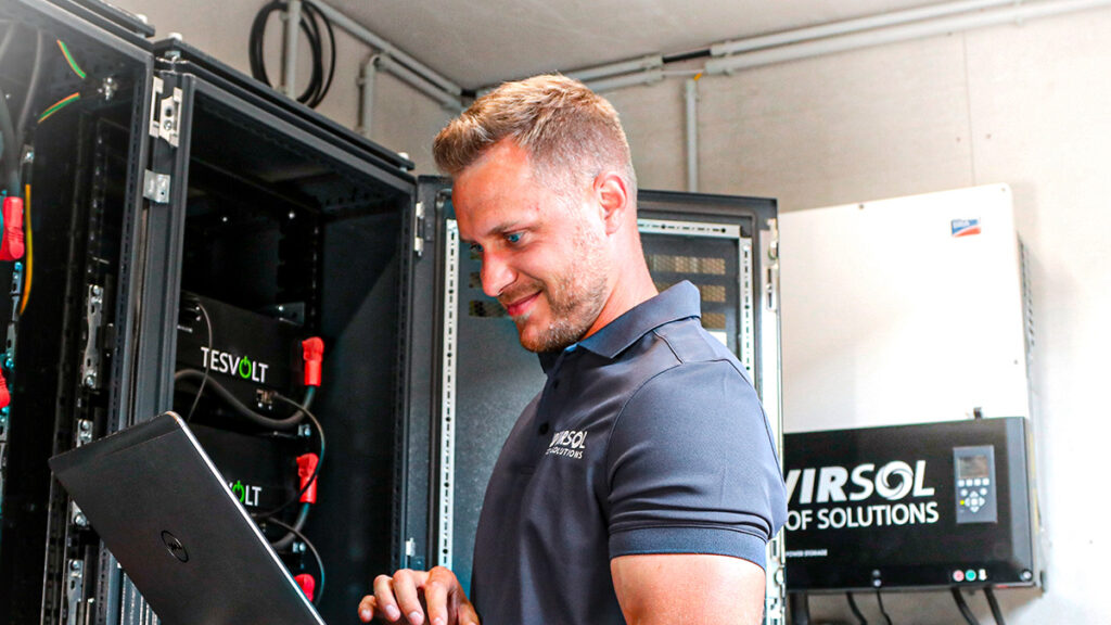 Ein Mann steht mit Laptop vor einem geöffneten Schaltschrank